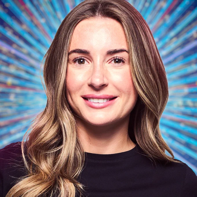 A head and shoulders shot of Dani Dyer, smiling for the camera against a glittering blue background.